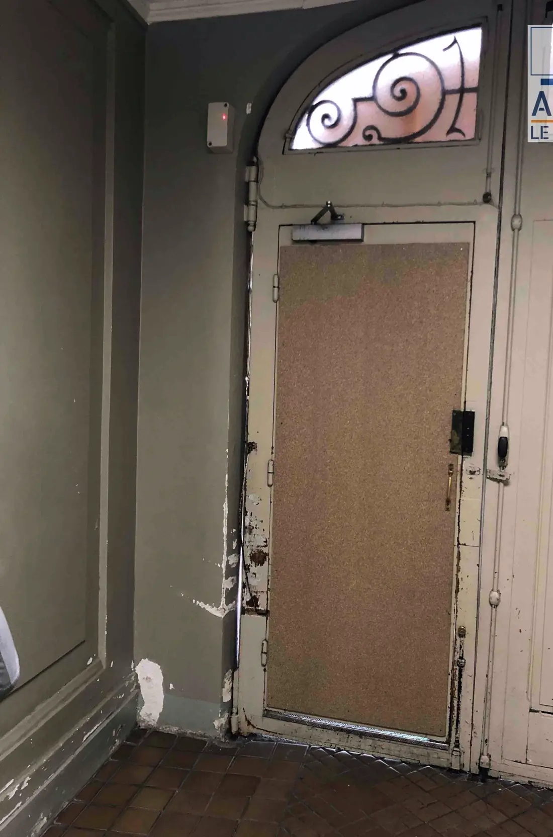Porte cochère vue du porche avant travaux, vantail doublé d’un panneau brut, imposte en fer forgé