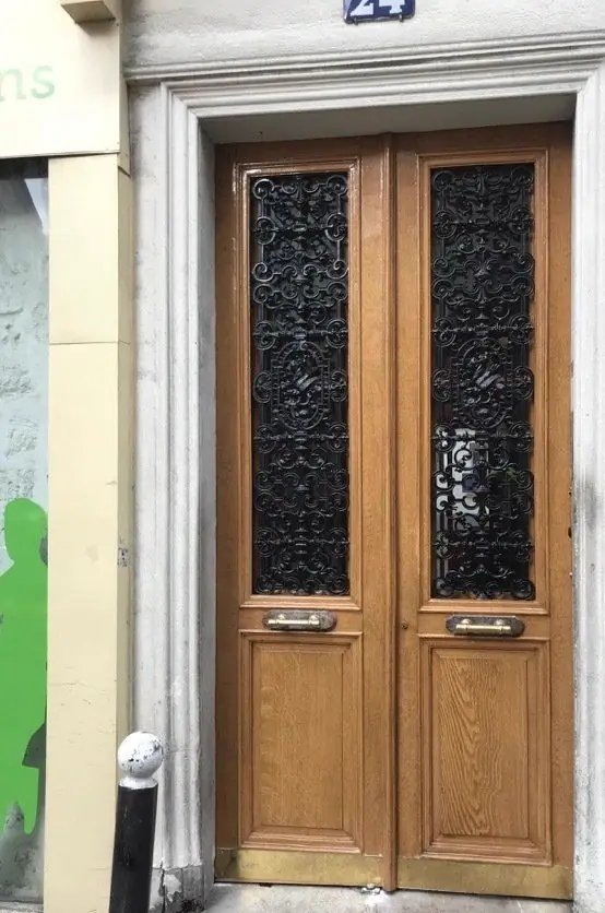 Porte bâtarde, 24 rue des Dames, Paris 17e — 2017 : Porte bâtarde restaurée : grilles de fonte dégagées, chêne remis en teinte claire, plinthe de laiton neuve.