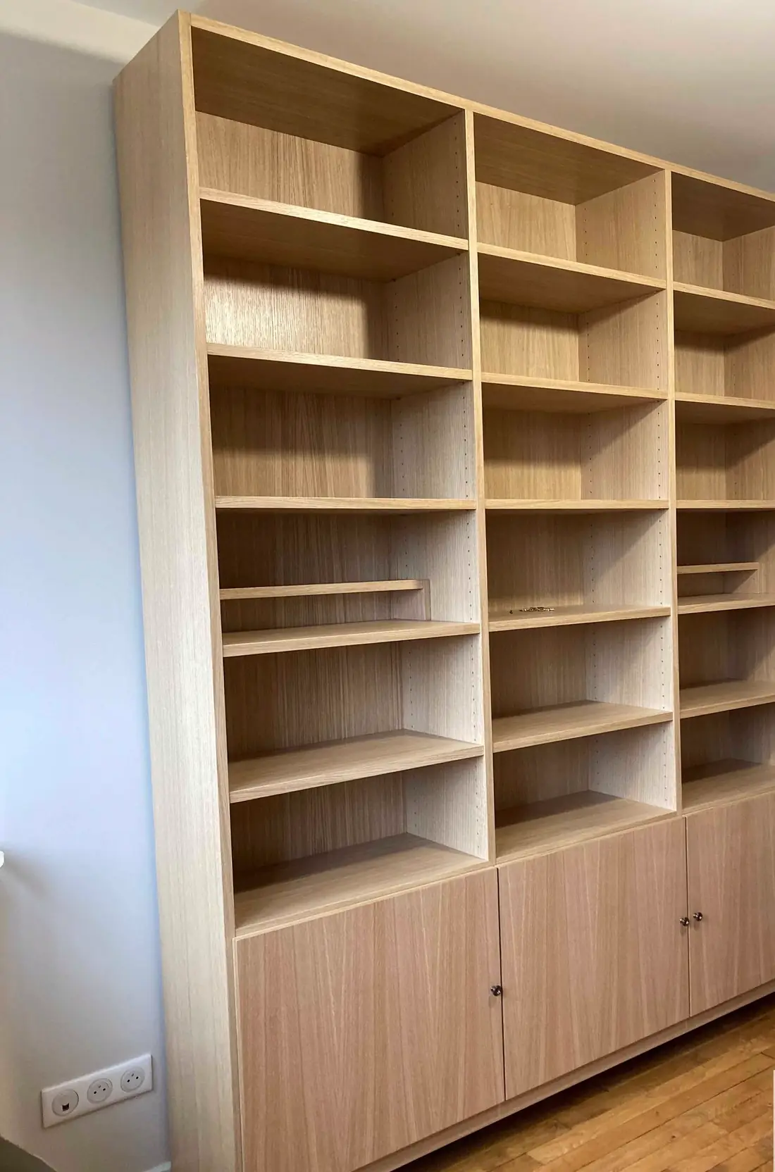 Bibliothèque en panneaux plaqués chêne clair, casiers ouverts et portes basses