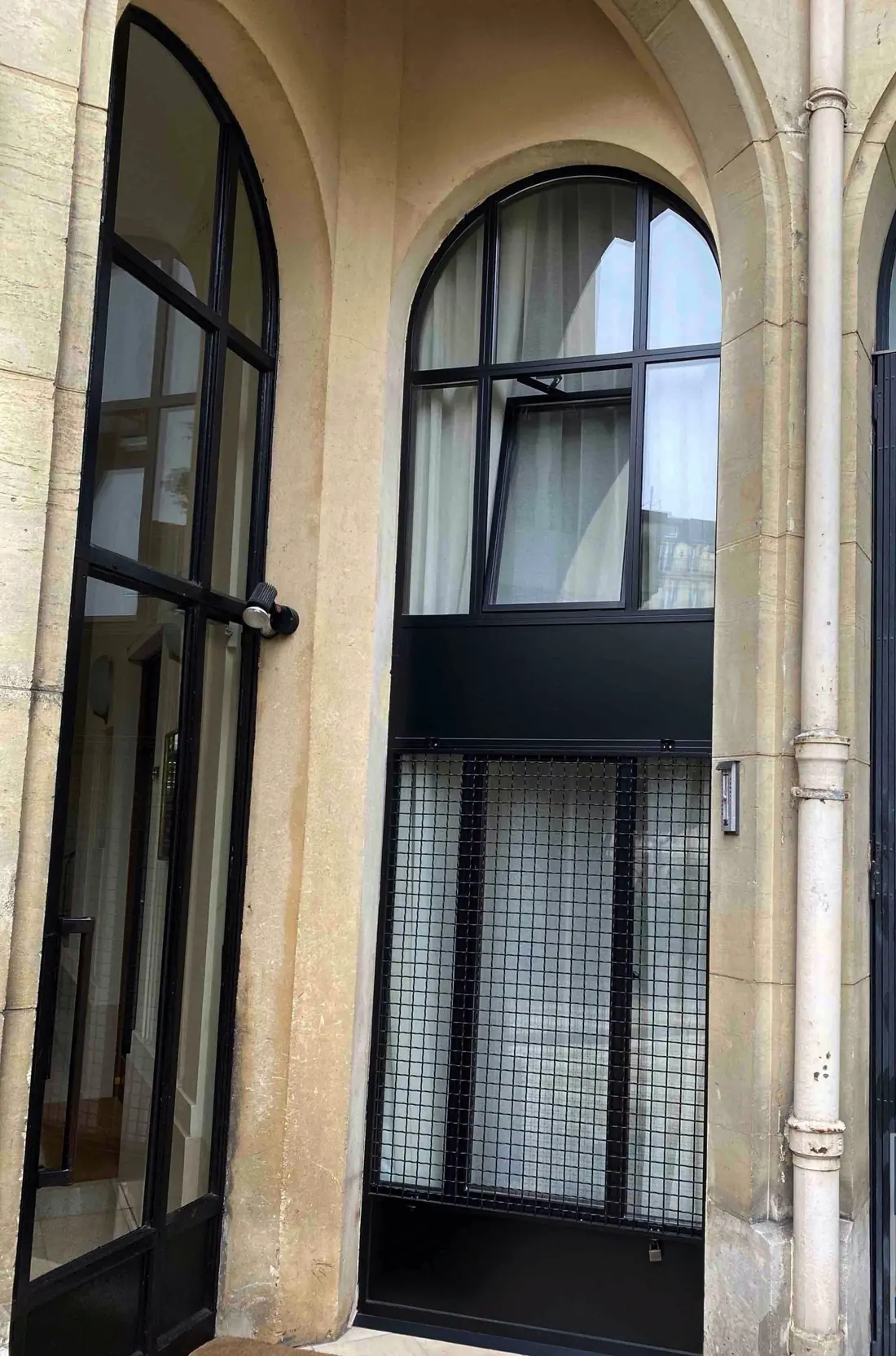 Châssis en acier noir à arcs surbaissés, vitrés, dans une cour ancienne