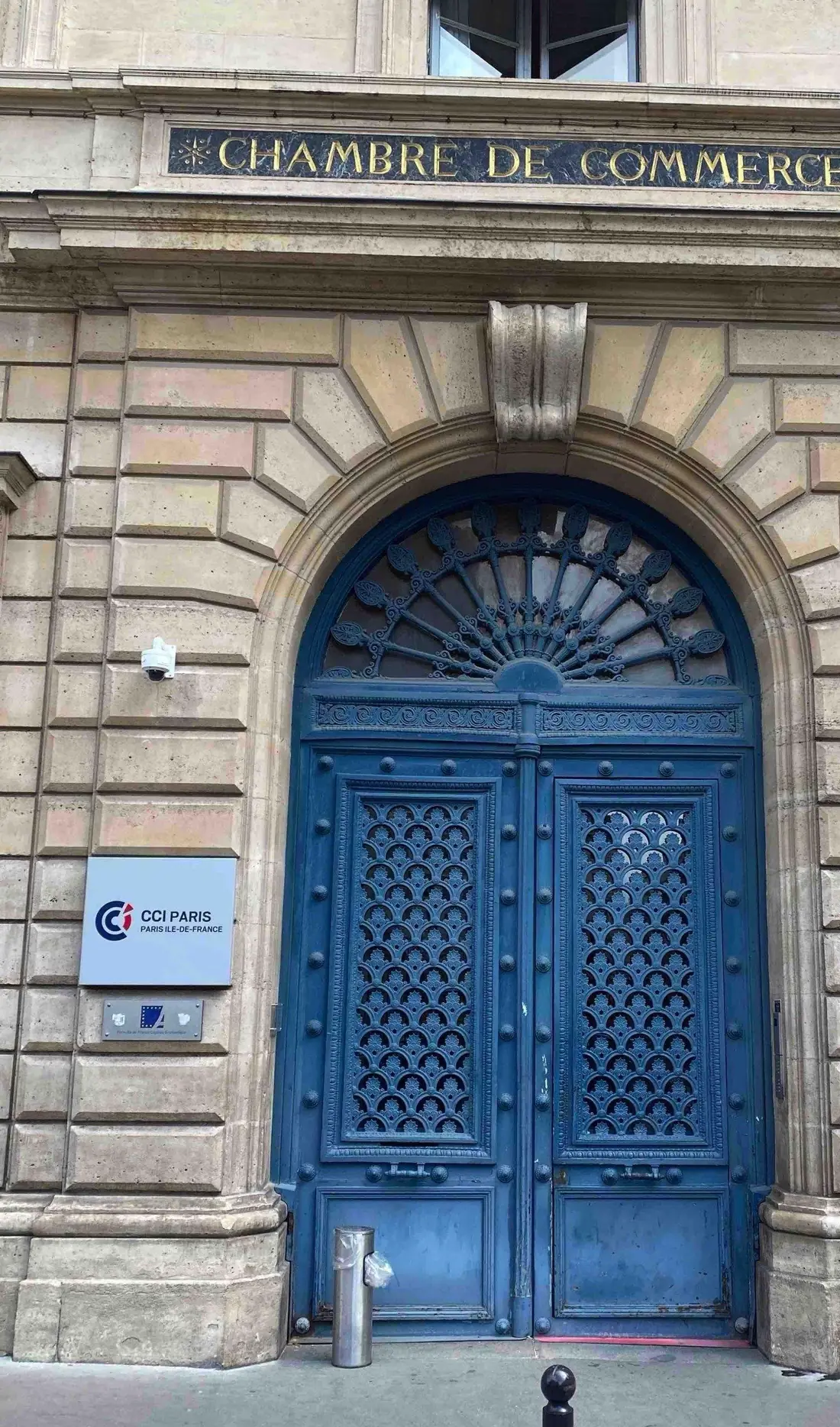 Porte bâtarde bleue cintrée à imposte grillagée, façade de pierre