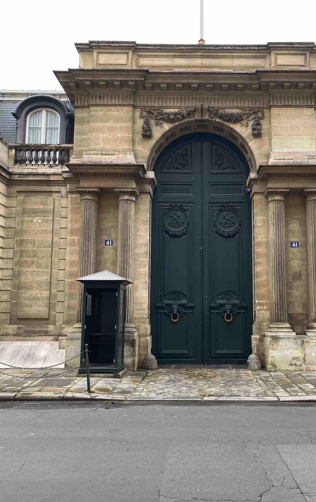 Porte cochère monumentale verte au fond d’un portail de pierre à fronton