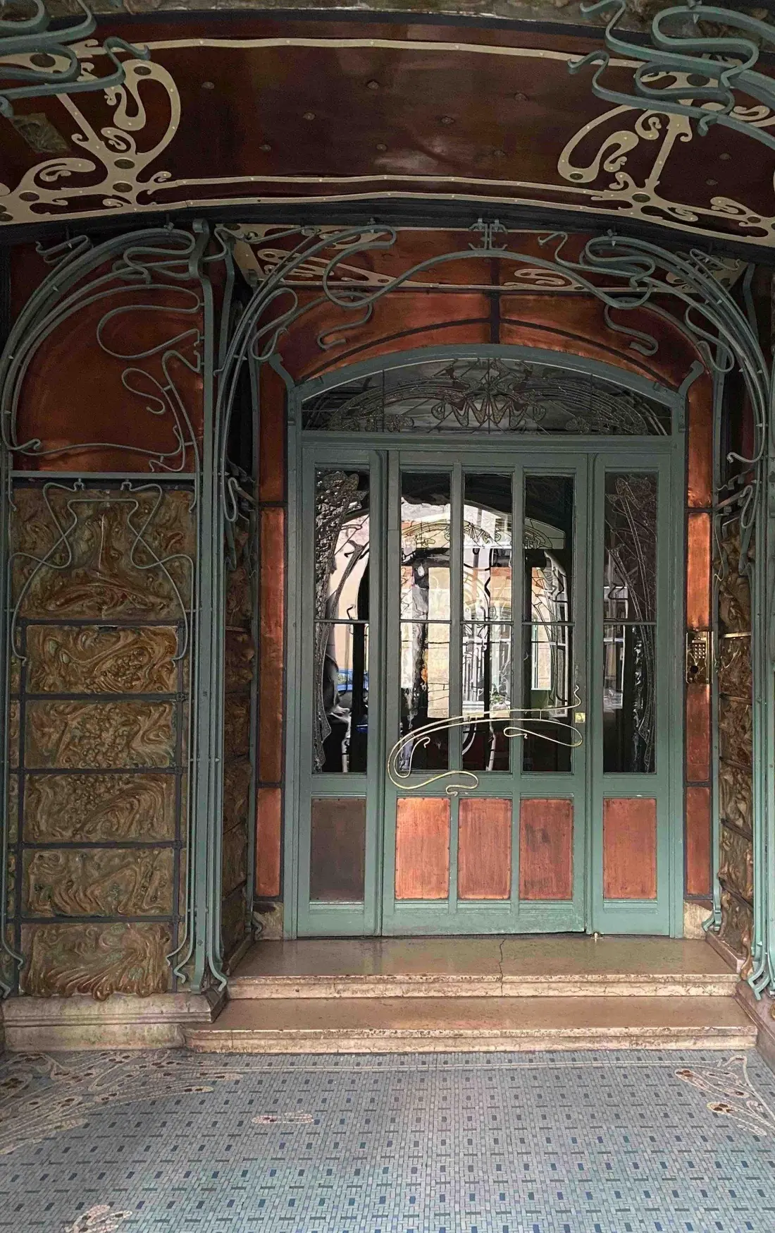 Porte de sas Art nouveau en fer et verre, vue depuis le porche d’un immeuble