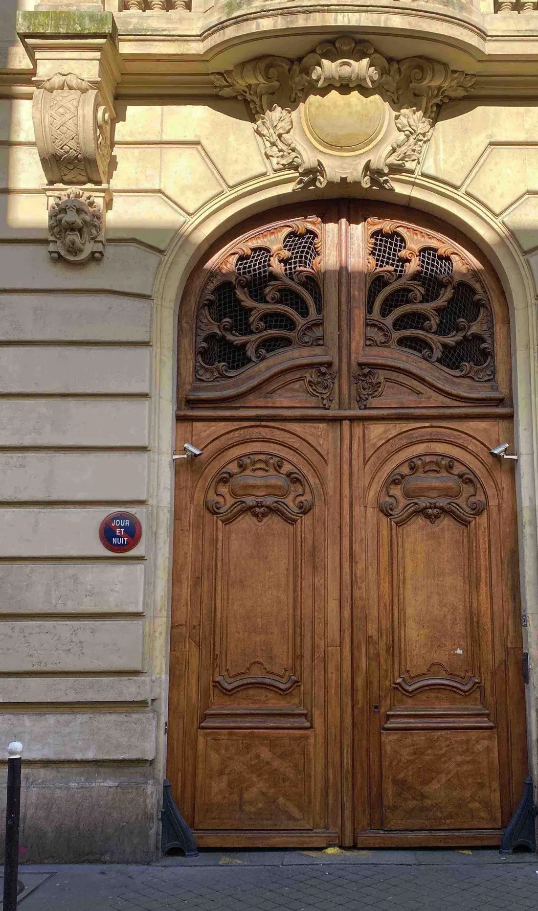 Porte cochère cintrée en bois sculpté sous un décor de pierre