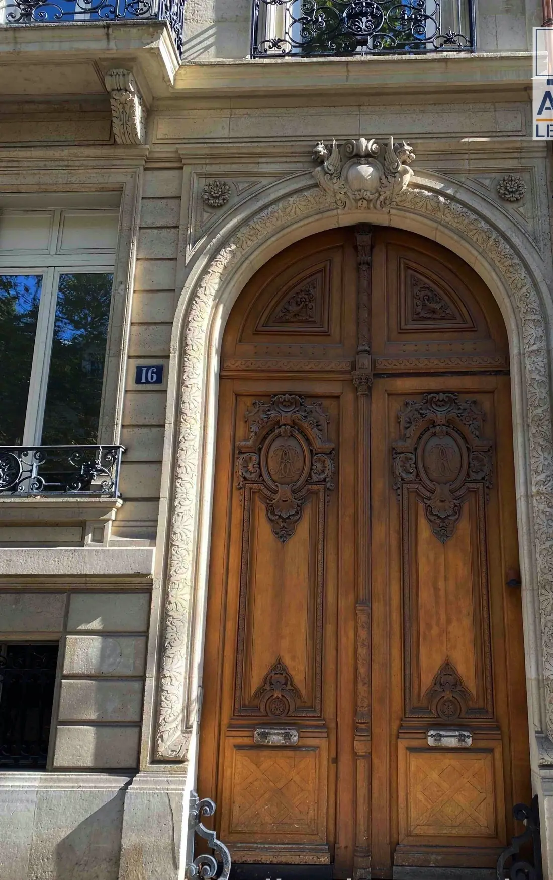 Porte cochère cintrée en bois verni sous une façade ornée