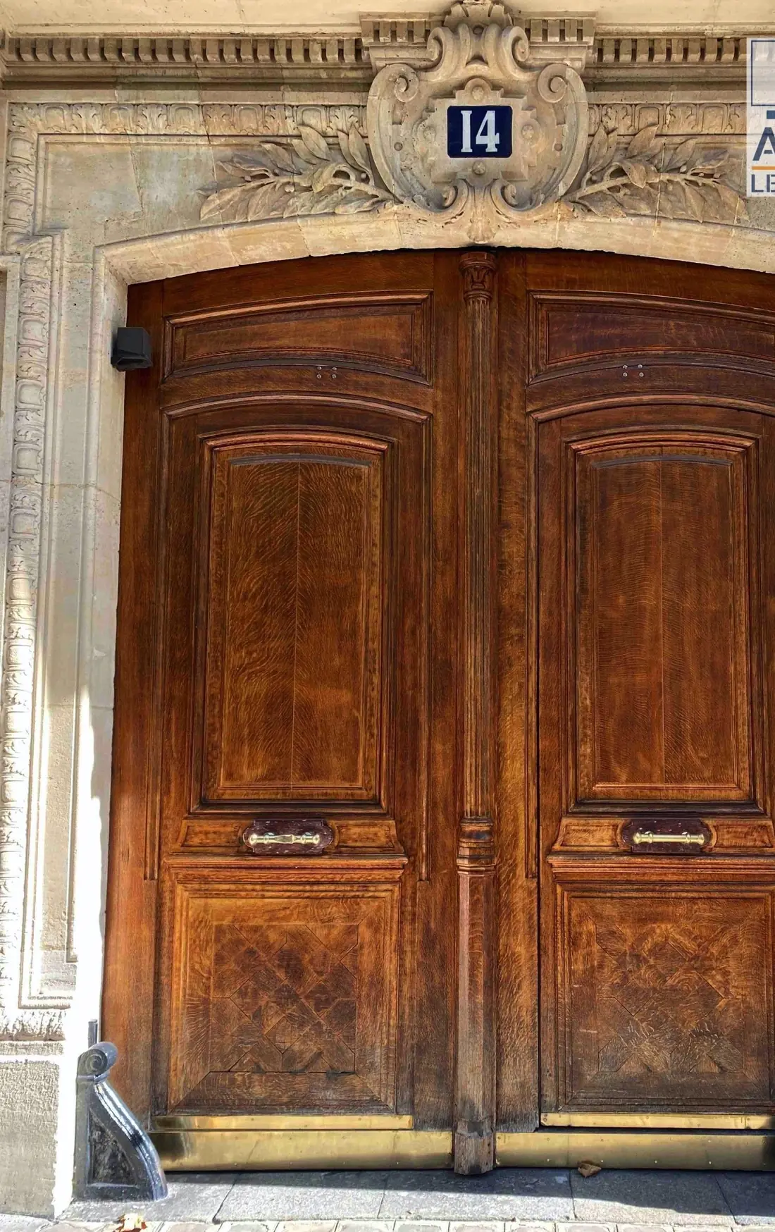 Porte cochère en bois ciré à panneaux sculptés, encadrement de pierre