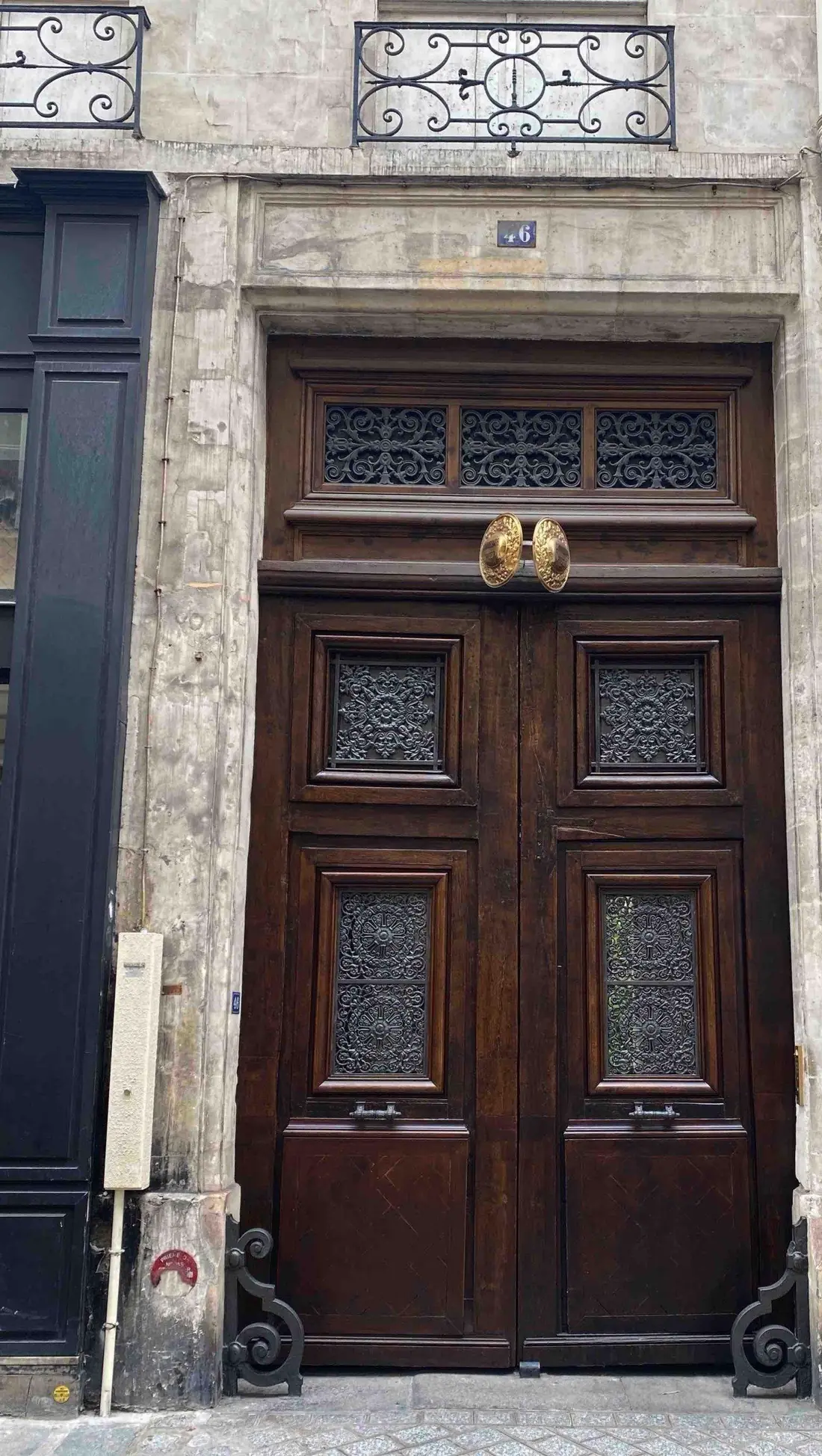 Porte bâtarde en bois sombre à panneaux moulurés, sous une imposte