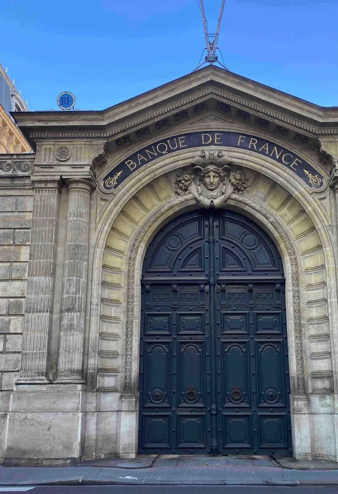 Porte cochère bleu nuit cintrée sous un grand arc de pierre sculpté