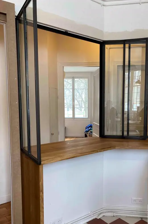 Cloison en acier et verre montée en angle au-dessus d’un plan de travail en bois