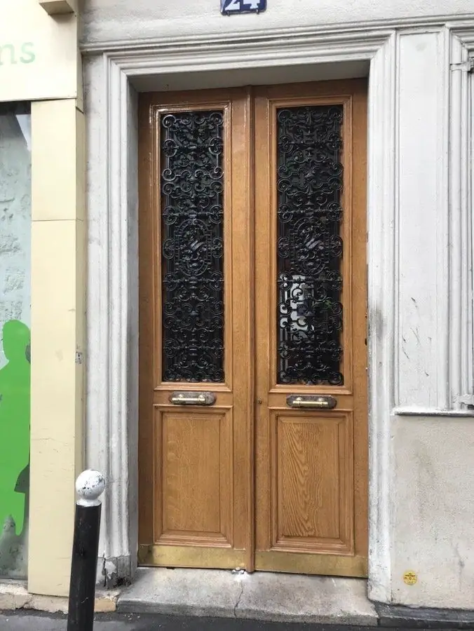 Porte bâtarde en chêne clair à deux vantaux, grilles de fonte dans les panneaux hauts