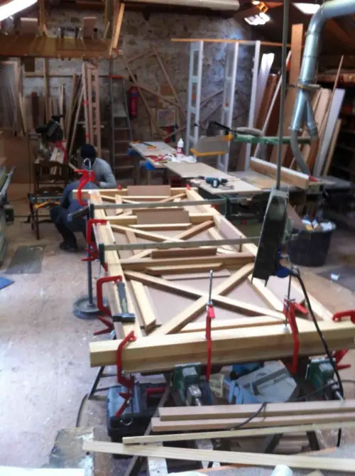Sections de garde-corps en bois assemblées et serrées sur les établis de l’atelier
