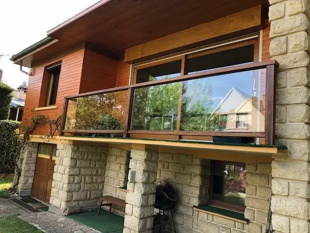 Garde-corps en bois et verre sur le balcon d’une maison à bardage de bois
