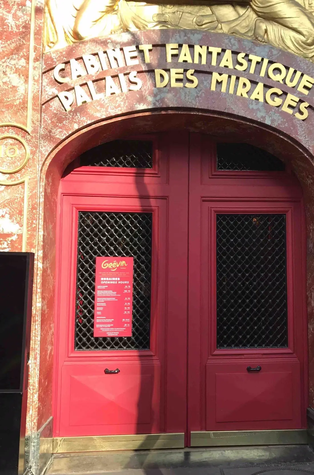 Porte rouge à grilles du Cabinet fantastique du musée Grévin, sous une enseigne peinte