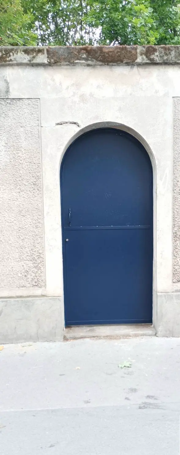 La même porte d’acier cintrée, relaquée en bleu