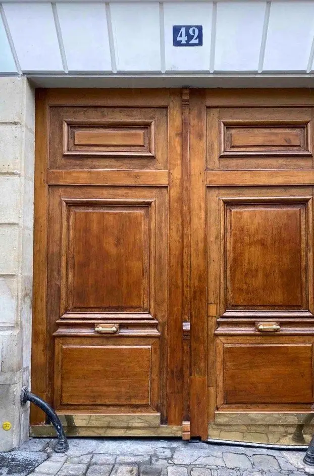 Porte cochère en chêne verni à deux vantaux, numéro 42, encadrée de chasse-roues en fonte
