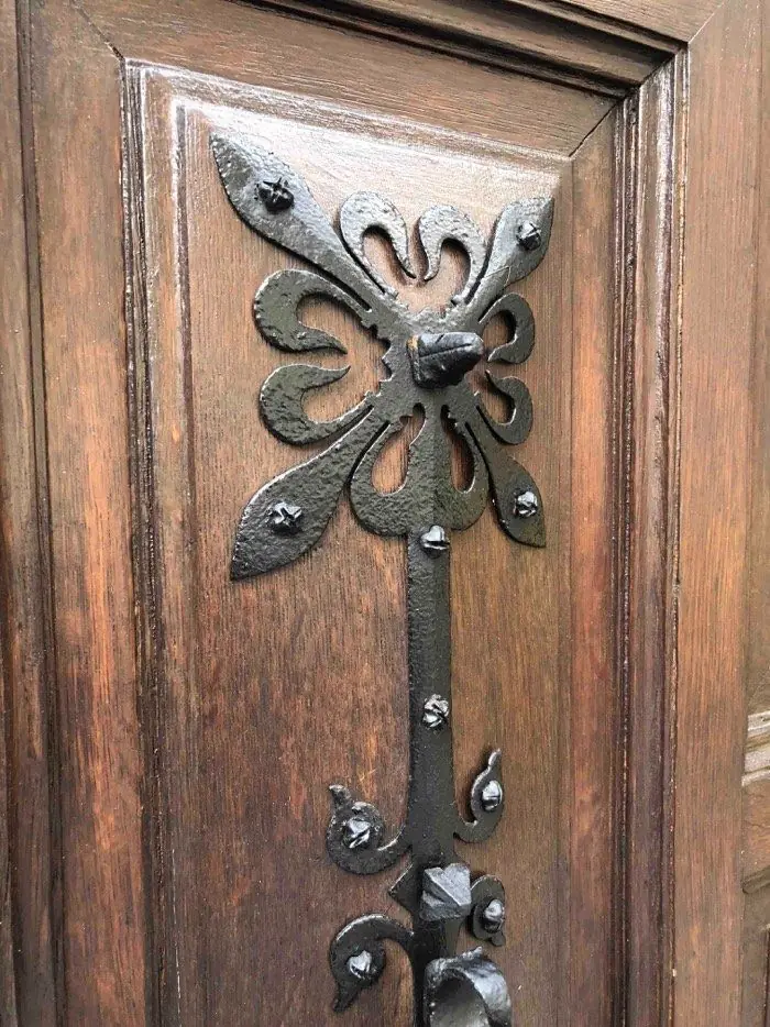 Penture forgée en fleuron clouée sur un panneau de chêne