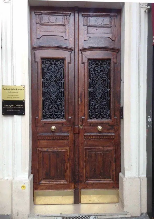 Porte d’immeuble à deux vantaux en chêne foncé, panneaux sculptés et grilles en fonte