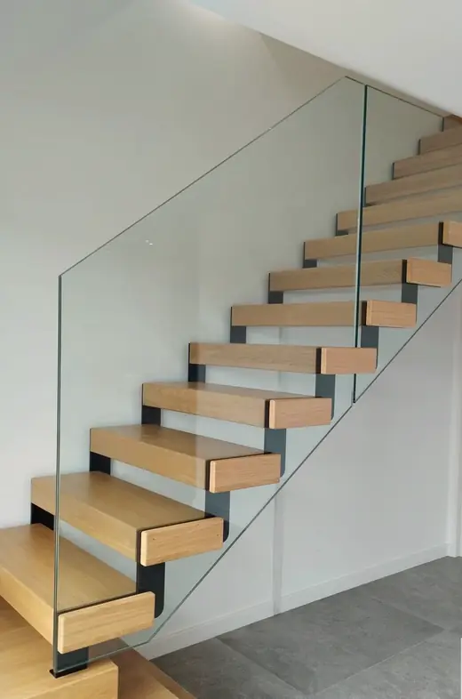 Escalier droit à marches de bois clair sur limon acier noir, garde-corps en verre