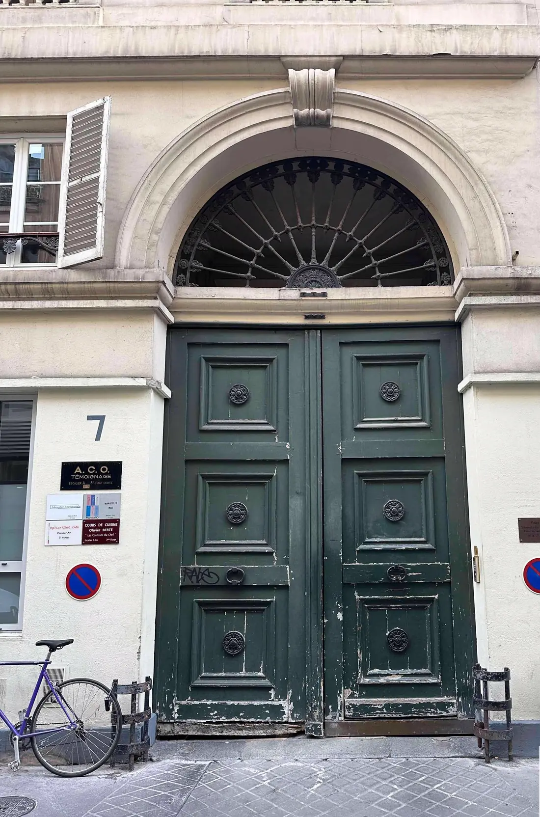 Porte cochère vert sombre sous un arc plein cintre à imposte en éventail, avant travaux