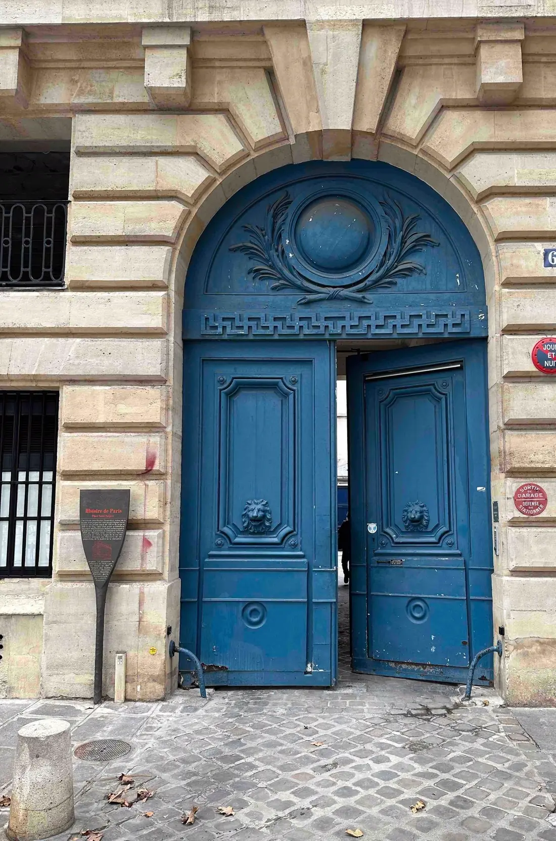 Porte cochère bleue à médaillon sculpté, portillon ouvert sur le porche