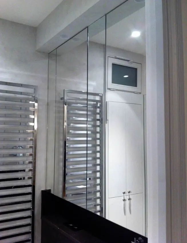 Salle de bain à cloison vitrée et miroirs muraux, sèche-serviettes au premier plan