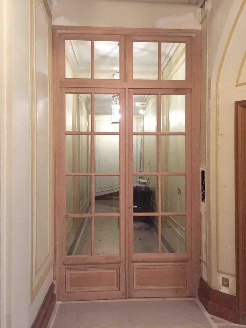 Porte de sas vitrée à petits bois en chêne, dans le hall d’un immeuble