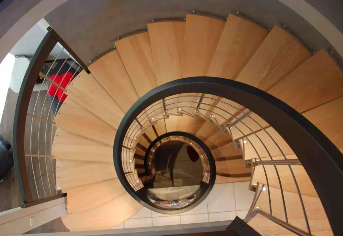 Vue plongeante sur un escalier hélicoïdal en bois à garde-corps courbe