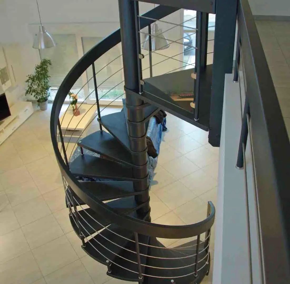 Escalier hélicoïdal en acier gris à barreaudage, vu depuis l’étage