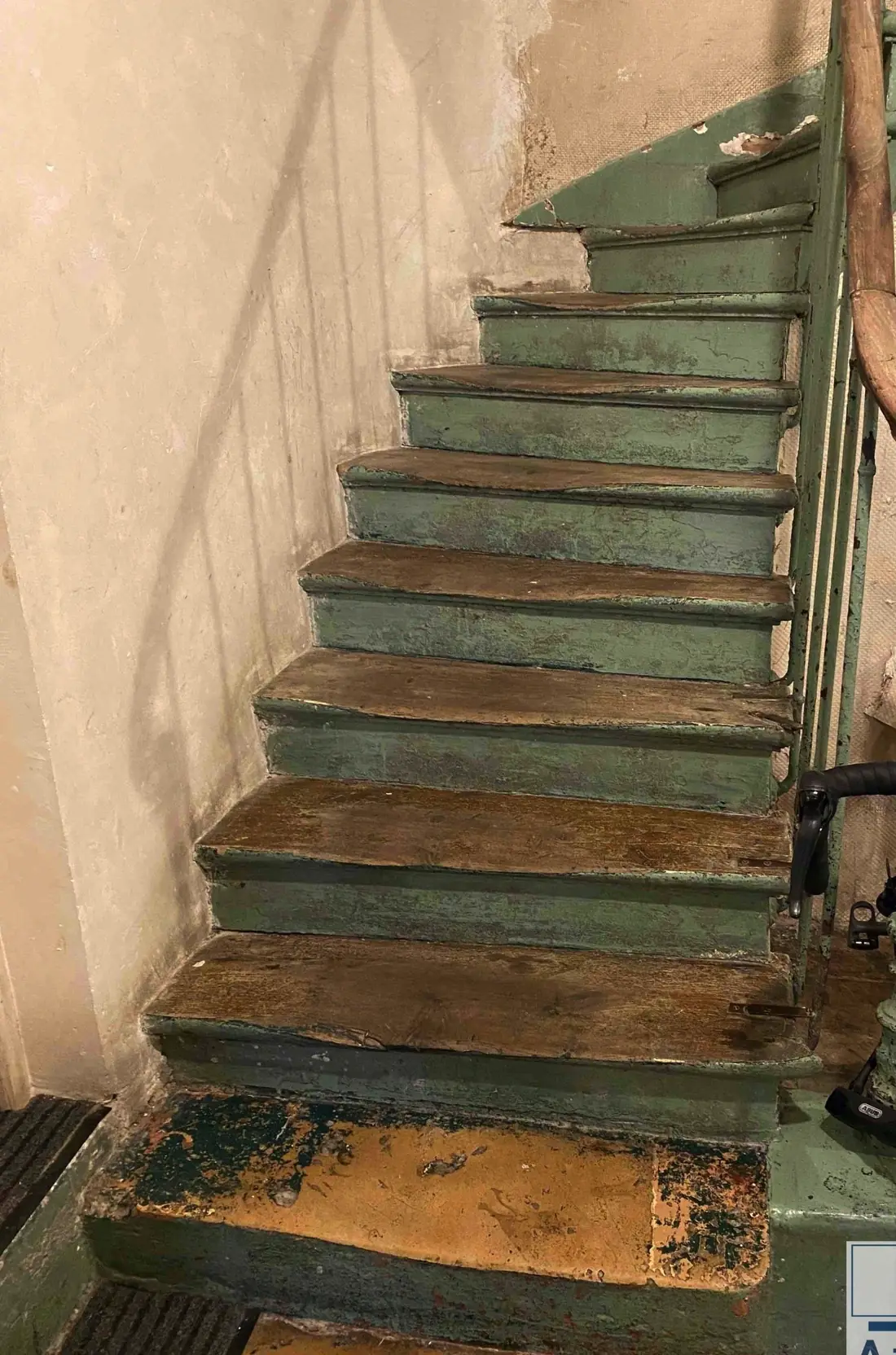 Escalier ancien aux marches peintes en vert, usées et écaillées, avant travaux