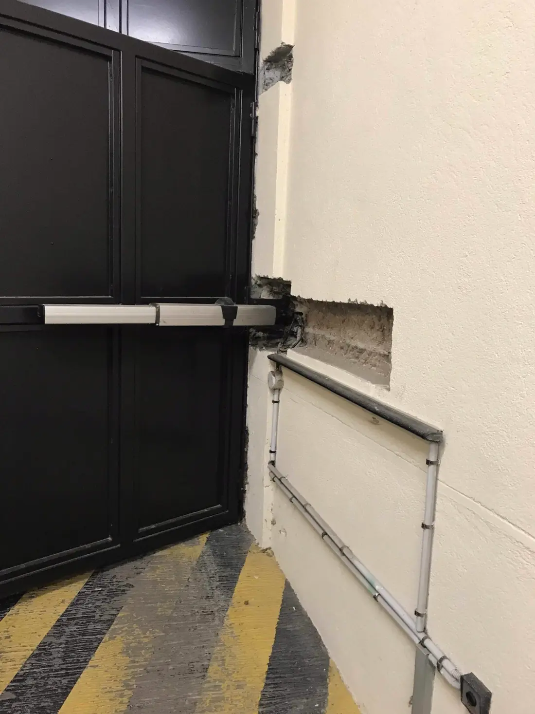 Vantail en acier laqué noir commandé par un vérin, bandes jaunes et noires au sol