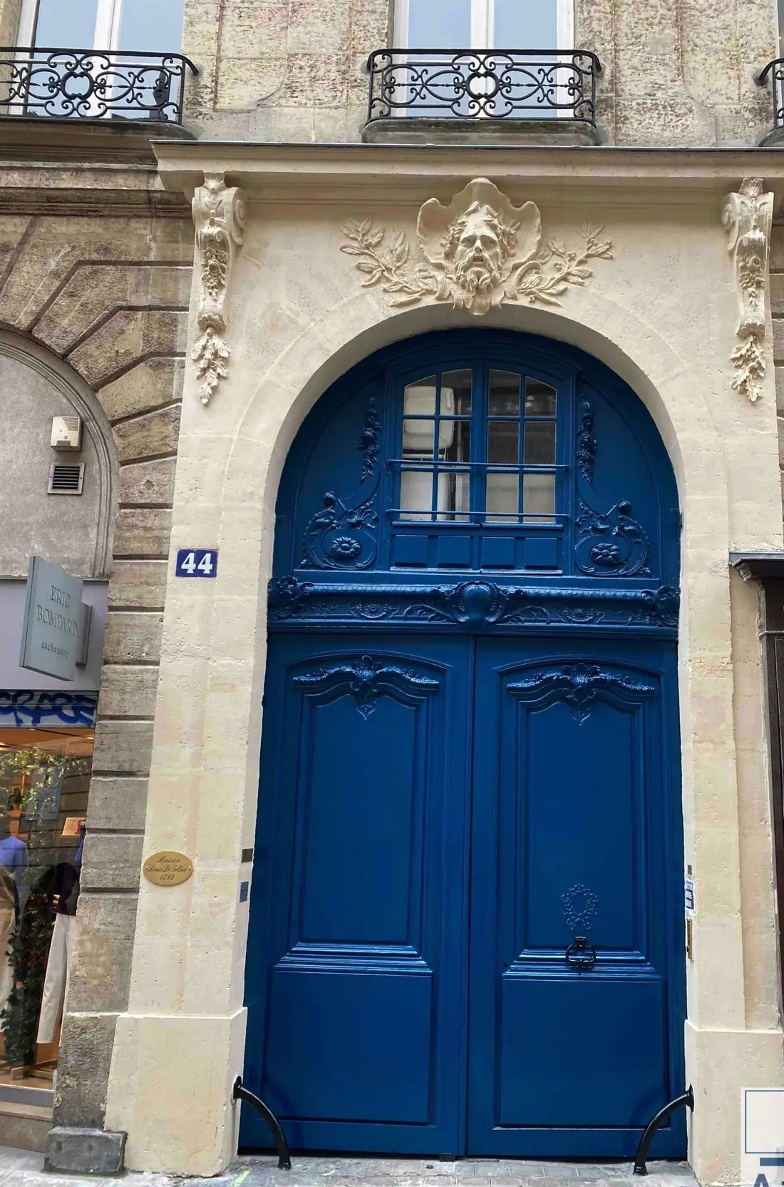 Porte cochère bleue sous un arc à mascaron, après restauration